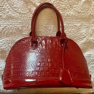 Red patent leather handbag with crocodile print.